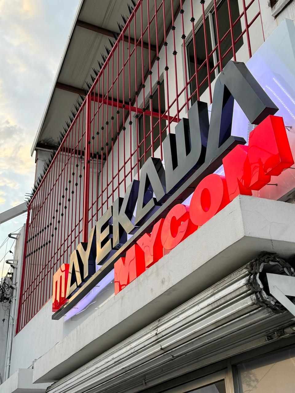 Letrero Mayekawa con halo de luz blanca — vista 2